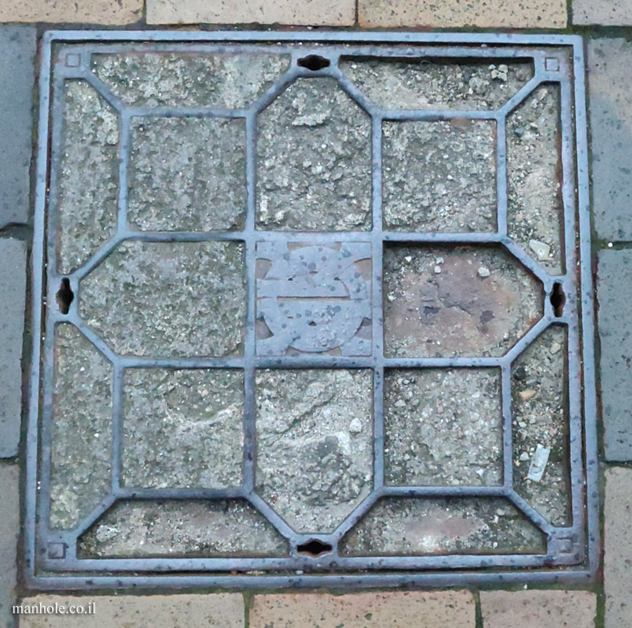 Odense - concrete cover crossed by metal strips and a logo in the center