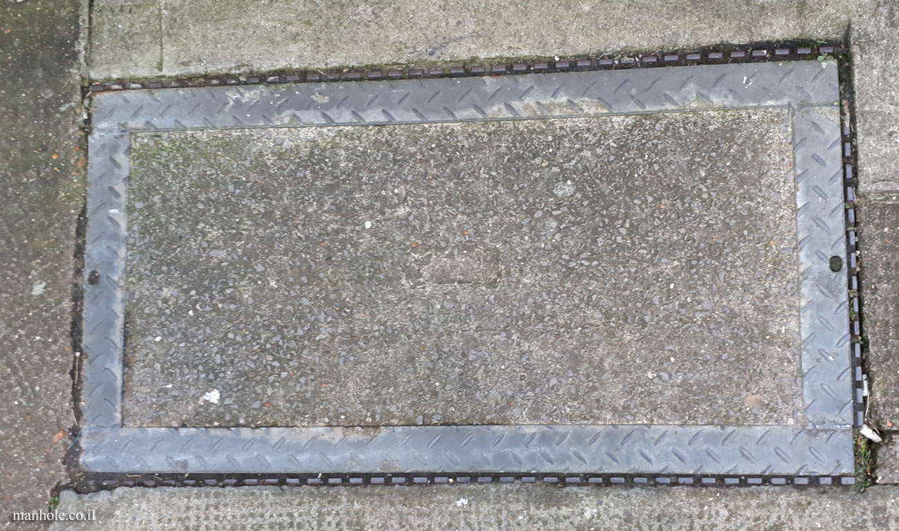 London - A rectangular concrete manhole cover with a thick metal frame with stripes